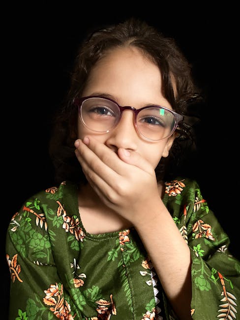 Ragazza con occhiali esprime shock o tristezza, possibile reazione alla notizia della morte a Crans-Montana, sguardo turbato e mano sulla bocca.