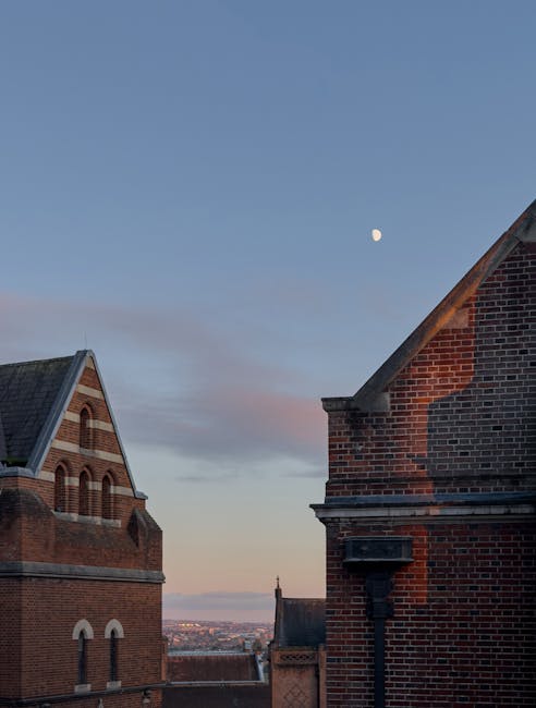 Scuola storica in mattone al tramonto con luna piena: esempio di edificio da ristrutturare per l'accessibilità e l'eliminazione barriere architettoniche.