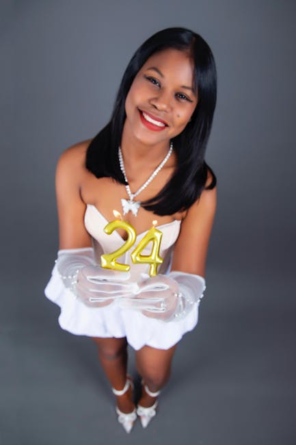 Ritratto di una donna sorridente che tiene candele dorate a forma di 24, simbolo di speranza e resilienza nel precariato scolastico.