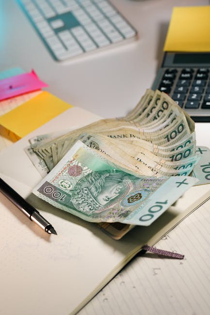 Assicurazione danni erariali consiglio d'istituto: banconote da 100 złoty su scrivania con calcolatrice e blocco note, simbolo di gestione finanziaria.