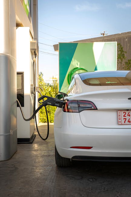 Auto elettrica bianca in ricarica presso stazione di servizio, focus su mobilità sostenibile e infrastrutture per veicoli elettrici