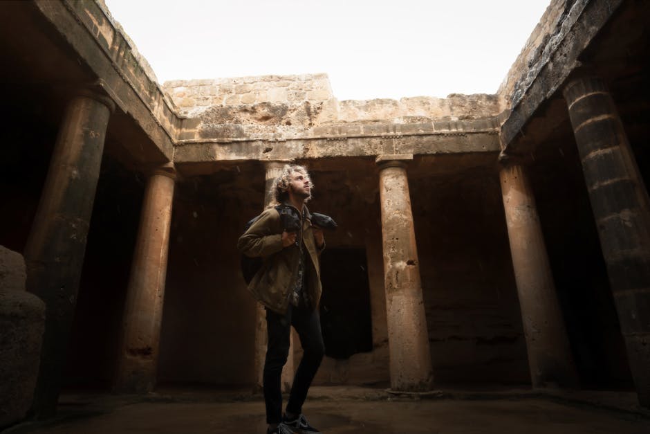 Turista esplora anfiteatro romano antico con colonne imponenti, testimonianza della storia e maestosità dell'architettura romana.