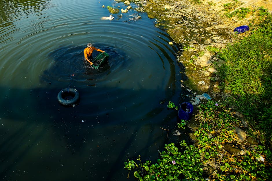 Uomo che pulisce un fiume inquinato con rifiuti e spazzatura, simbolo della lotta contro l'inquinamento ambientale e la necessità di un mondo più responsabile.