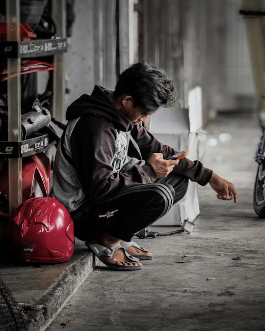 Ragazzo accovacciato che usa lo smartphone, un'immagine che riflette l'uso attento dei dispositivi digitali in età adolescenziale.