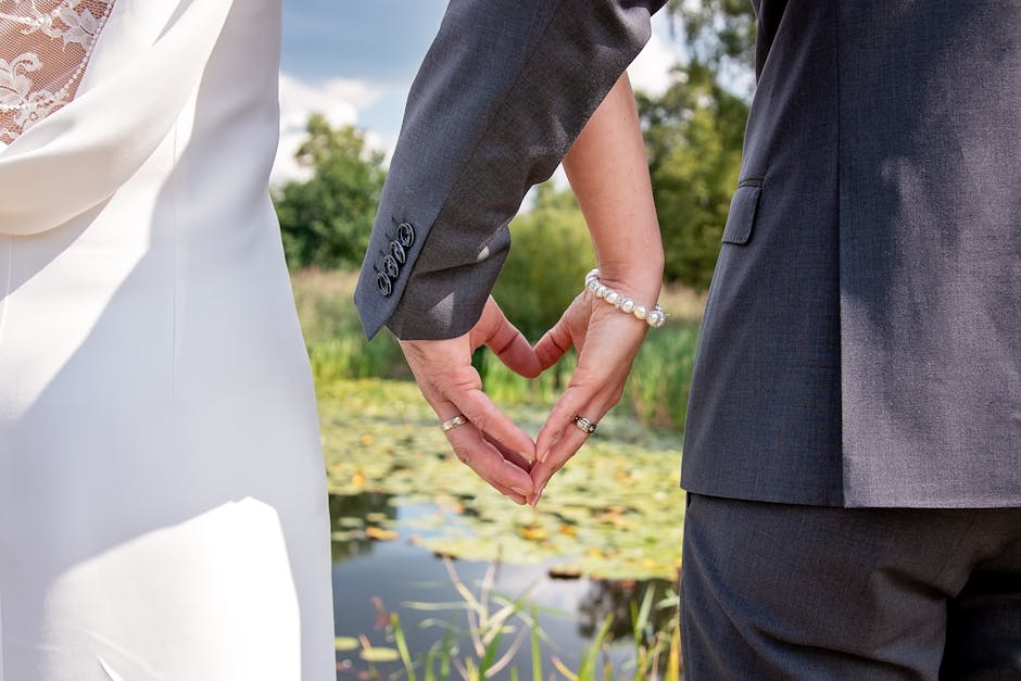 Matrimonio docenti Piacenza: mani degli sposi formano un cuore con le dita, anelli nuziali in primo piano, simbolo dell'unione celebrata
