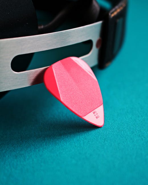 Plettro rosa appoggiato a cuffie: strumento musicale per plasmare emozioni e comportamenti attraverso la musica.