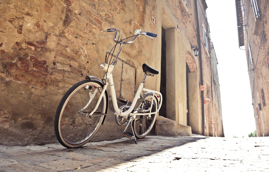 Bicicletta vintage bianca appoggiata a muro di mattoni in un vicolo italiano, evocativa di tempi passati e della bellezza senza tempo.