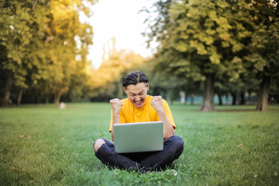 Studente asiatico esulta con laptop all'aperto, successo scolastico e valutazione individualizzata, approccio personalizzato all'apprendimento
