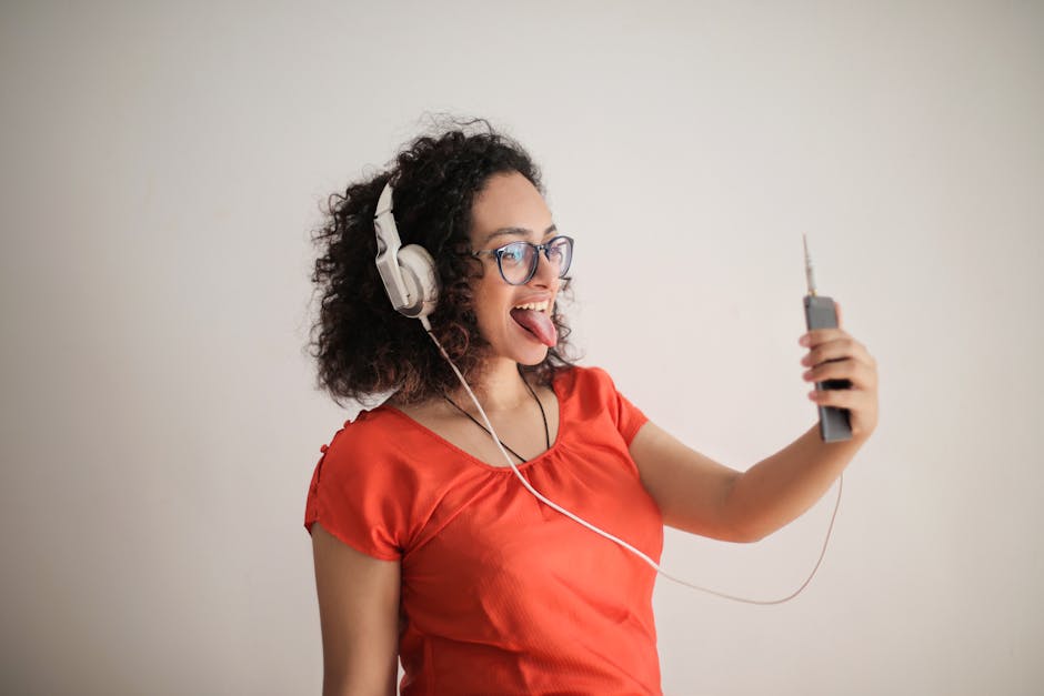 Ragazza sorridente con cuffie che ascolta inglese e fa esercizi di pronuncia divertenti con app sul telefono.