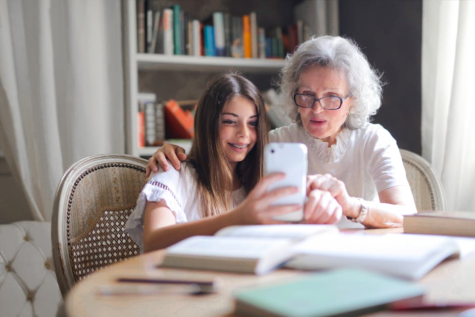 Nonna e nipote leggono insieme su smartphone, libri aperti sul tavolo. Carta Cultura giovani per acquisto libri dal 1 al 31 ottobre.