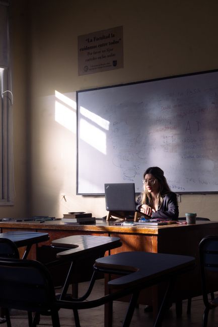 Docente lavora al computer in aula con lavagna e banchi, simbolo di apprendistato duale