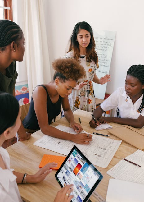 Gruppo di donne che collaborano a un progetto utilizzando tecnologie digitali e strumenti tradizionali per l'innovazione e la comunicazione.
