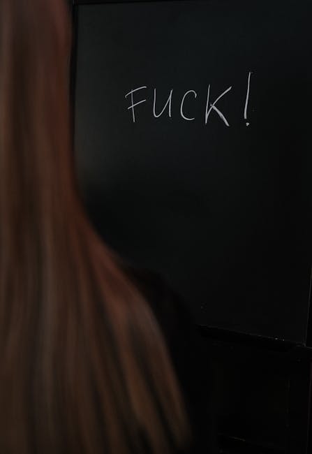 Scritta volgare su lavagna nera in classe, simbolo di protesta o disagio giovanile nel contesto dell'educazione sessuale.