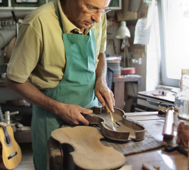 Artigiano liutaio al lavoro su uno strumento musicale, simbolo della cultura come resistenza e cittadinanza attiva