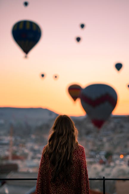 Donna ammira mongolfiere all'alba in Cappadocia: un'esperienza bucolica immersa nella bellezza della natura e del paesaggio unico.