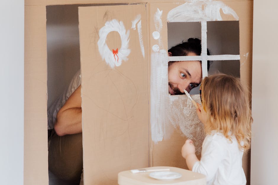 Padre e figlia dipingono una casa di cartone insieme, promuovendo un'educazione attiva e creativa, lontano dal modello del padre peluche.