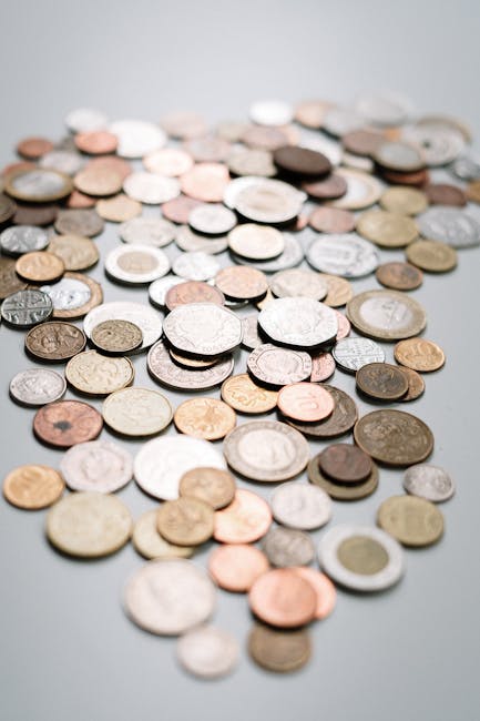 Arrotondamento finanziario: immagine ravvicinata di diverse monete sparse, simbolo di gestione precisa del denaro e delle finanze personali.