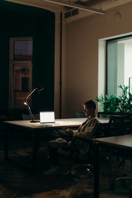 Insegnante stanco lavora tardi al computer con smartphone, strategie per rimanere focalizzati e produttivi nonostante il carico di lavoro
