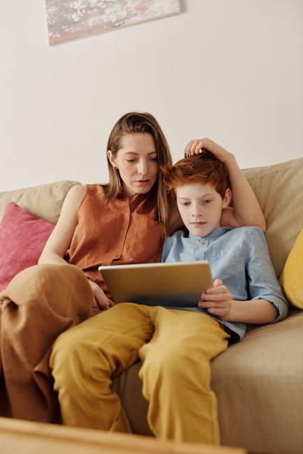 Madre e figlio con tablet sul divano. Predizione altezza figlio e fattori di crescita per una corretta valutazione dello sviluppo infantile.