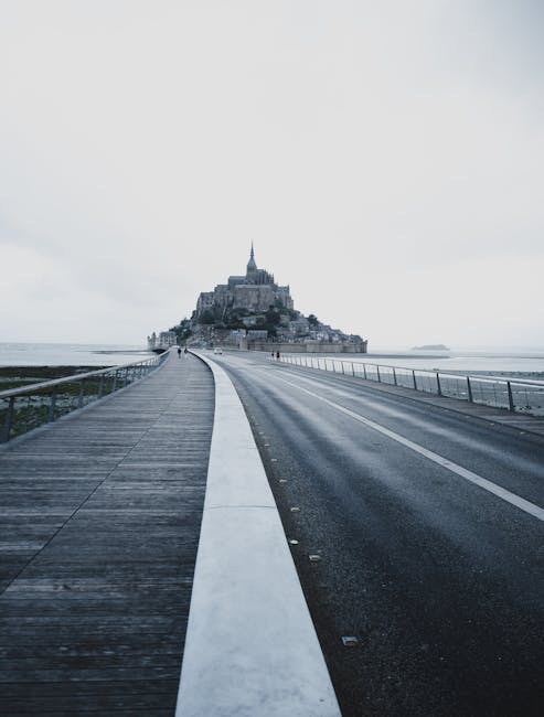 Mont Saint-Michel in Normandia, Francia, simbolo di scambio culturale e patrimonio UNESCO, visto da un ponte che rappresenta un viaggio