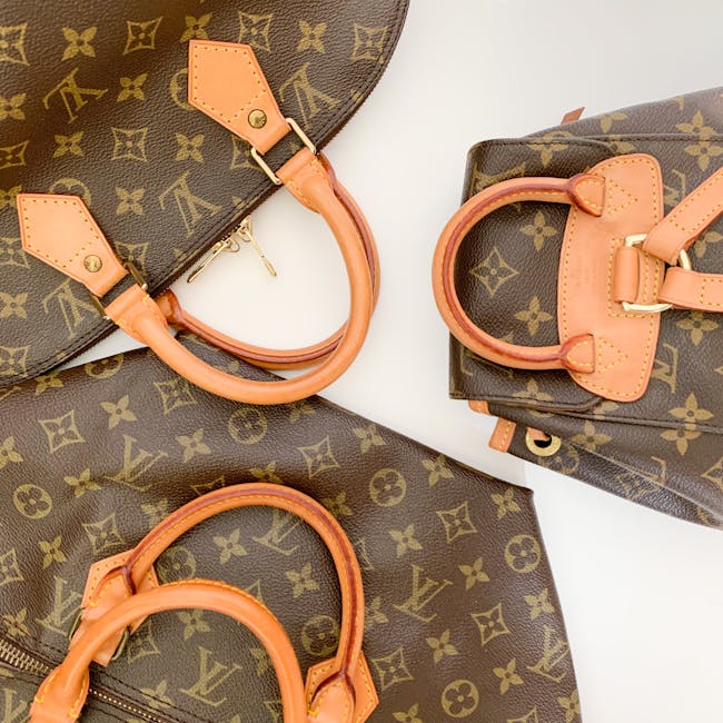 Dettaglio di borse in pelle con monogramma iconico, manici in cuoio chiaro. Pelletteria di lusso e design distintivo per un accessorio moda senza tempo.