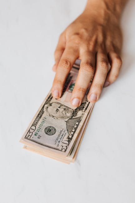 Incrementi salariali ATA: mano su banconote da 50 dollari, simbolo delle nuove posizioni economiche con retroattività da settembre 2024.