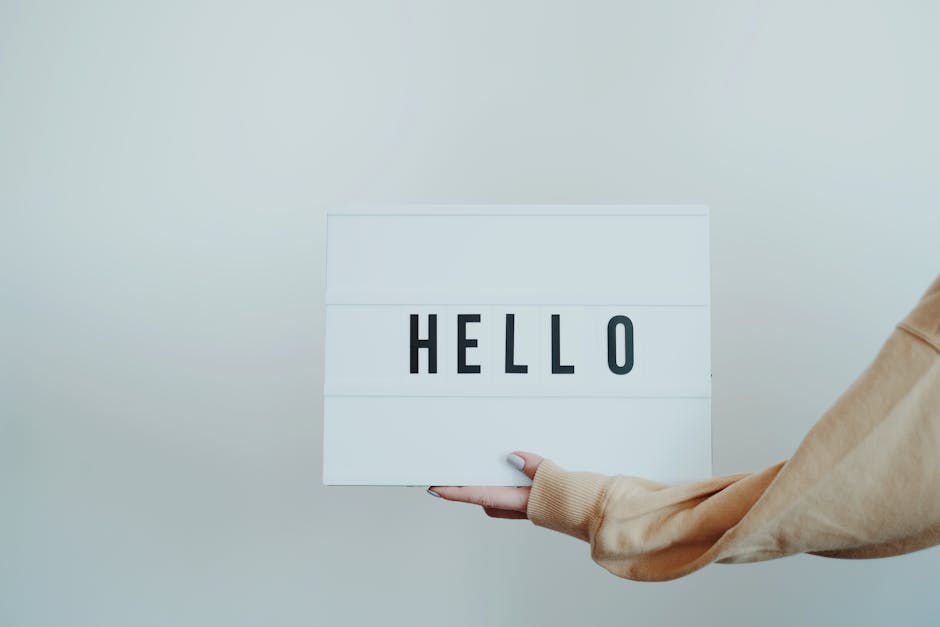 Insegnante madrelingua inglese accoglie studenti con cartello luminoso Hello. Corsi di inglese con docenti qualificati e certificati.