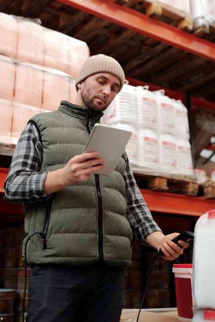 Addetto alla logistica verifica le assenze del personale scolastico tramite tablet e lettore di codici a barre in magazzino.