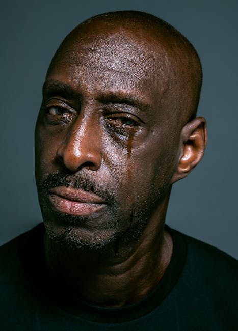 Primo piano di un uomo afroamericano con una lacrima che scende, espressione di profonda emozione e vulnerabilità, concetto di intorno emotivo.