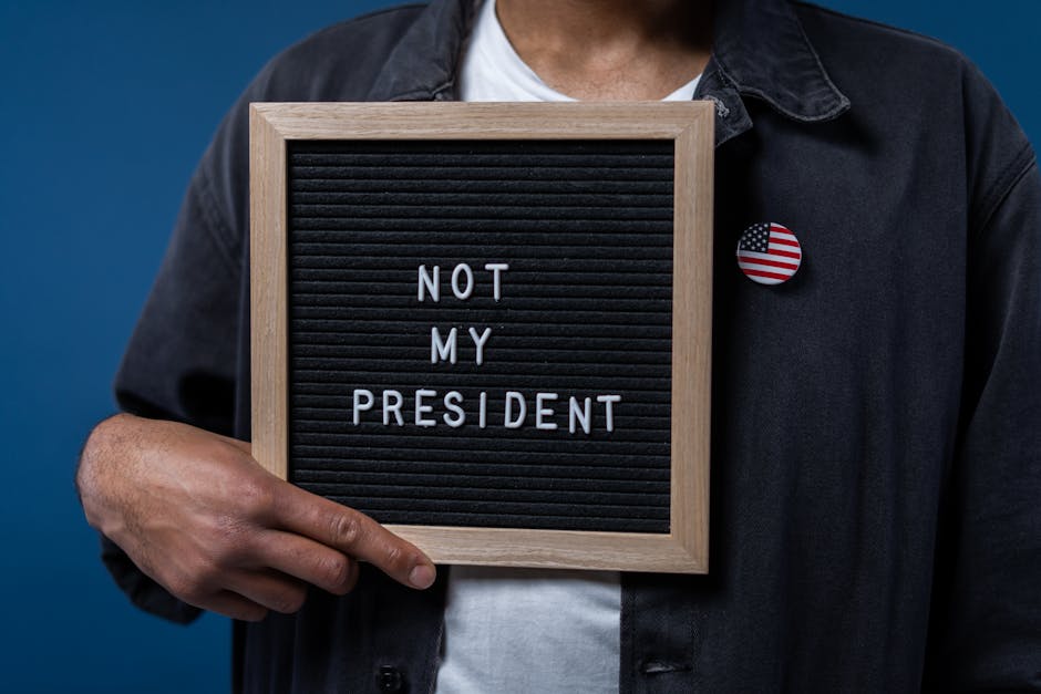 Persona che mostra cartello con scritta Not My President e spilla bandiera USA, implicazioni per il Garante della disabilità