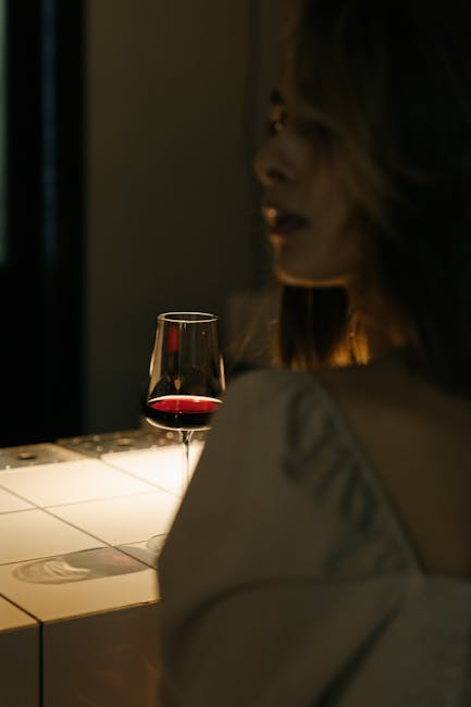 Donna con bicchiere di vino rosso in un ambiente intimo, riflessione sulla valutazione peer e sul feedback costruttivo