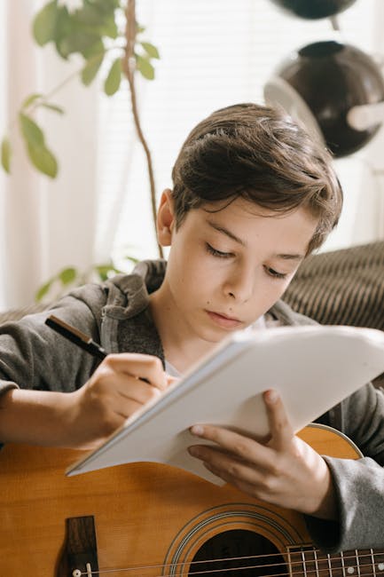 Ragazzo che compone musica con chitarra e quaderno, espressione concentrata, educazione musicale e creatività