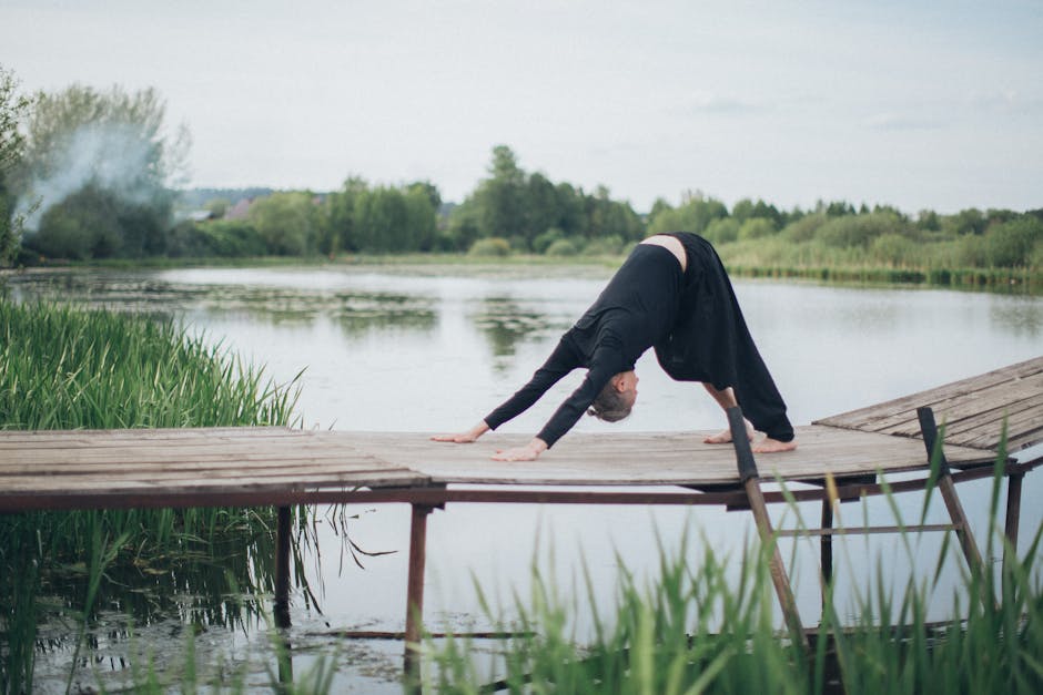 Donna pratica yoga all'aperto su piattaforma di legno vicino al lago, benessere personale ATA e sconti per la salute e il relax.