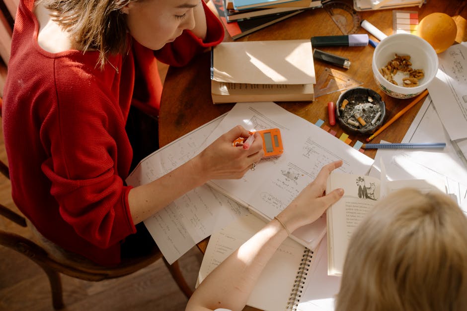 Studentesse che studiano insieme con libri e appunti sparsi sul tavolo, evidenziatore e snack per la preparazione agli esami universitari