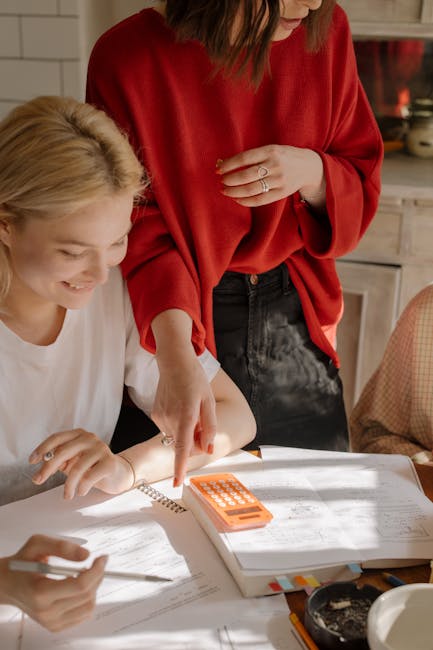 Collaborazione e studio per le posizioni ATA: due donne esaminano documenti e calcolatrice, preparazione alla prova finale rinviata.