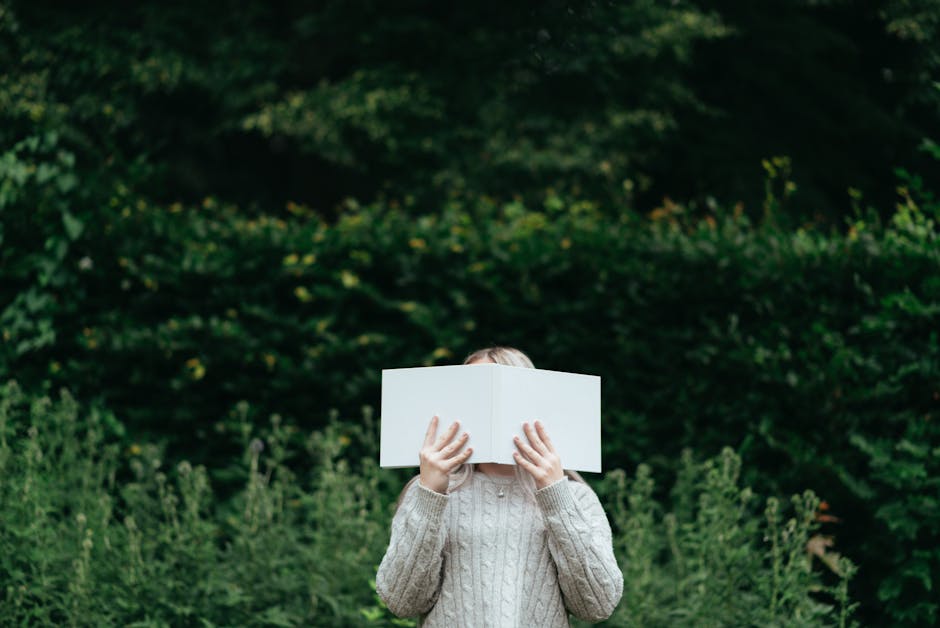 Donna che legge un libro bianco davanti a un rigoglioso sfondo verde, simbolo di apprendimento e crescita personale.