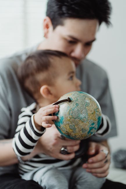 Bambino esplora il mondo con un mappamondo giocattolo in braccio al padre, apprendimento precoce attraverso il gioco e la musica.