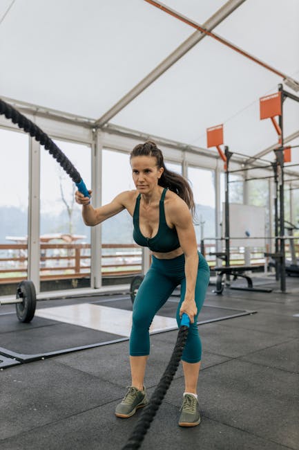 Donna che si allena con le funi da battaglia in palestra, bruciando calorie e migliorando la forma fisica con l'esercizio fisico.