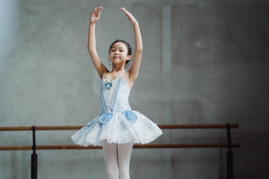 Bambina asiatica in tutù azzurro durante lezione di danza classica, possibile riferimento a malore improvviso a scuola e necessità di soccorso immediato.
