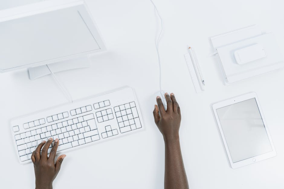 Mani che utilizzano tastiera, mouse e tablet bianchi per massimizzare la produttività con strumenti virtuali e stile di utilizzo efficace.
