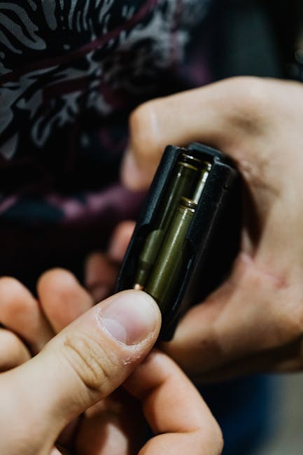 Caricatore di proiettili in mano, dettaglio. Rischio armi a scuola: Mantova e Costa Azzurra, un problema crescente e allarmante.