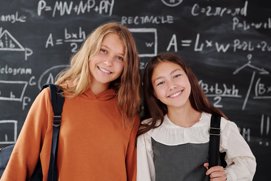 Due studentesse sorridenti davanti a una lavagna con formule matematiche, tema sull'uso dell'IA nei compiti scolastici.