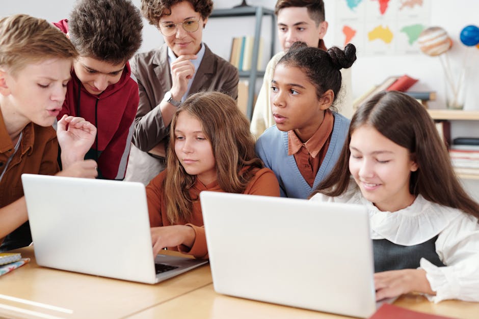 Studenti e insegnante collaborano a un progetto scolastico con i laptop, esempio di insegnamento basato sui progetti e pratiche vincenti.