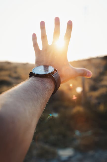 Mano tesa verso il sole con orologio da polso, metafora del tempo e dei viaggi nello spazio e negli anni luce