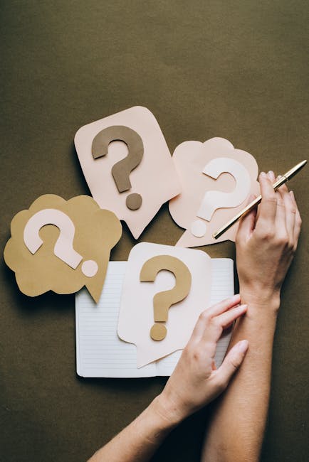 Punti interrogativi su carta e mano con penna, metafora di decisioni consapevoli e comprensione dell'utilità per scelte informate.
