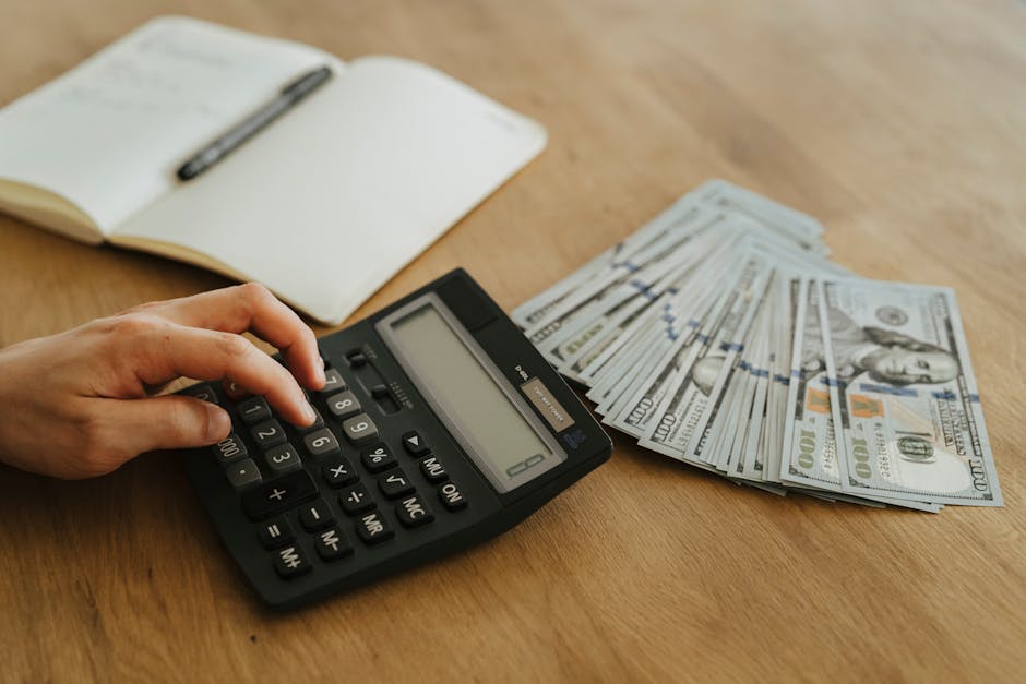 Calcolatrice, banconote da 100 dollari e quaderno per il piano annuale dei flussi di cassa MIM con scadenza 28 febbraio.
