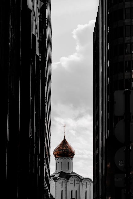 Contrasto tra architettura moderna e tradizionale: cupola dorata di chiesa ortodossa incorniciata da grattacieli in bianco e nero.