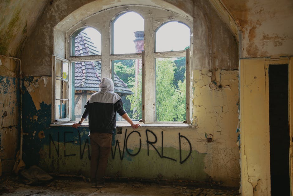 Figura di spalle guarda fuori dalla finestra di una stanza abbandonata con scritta New World, concetto di prospettiva e cambiamento
