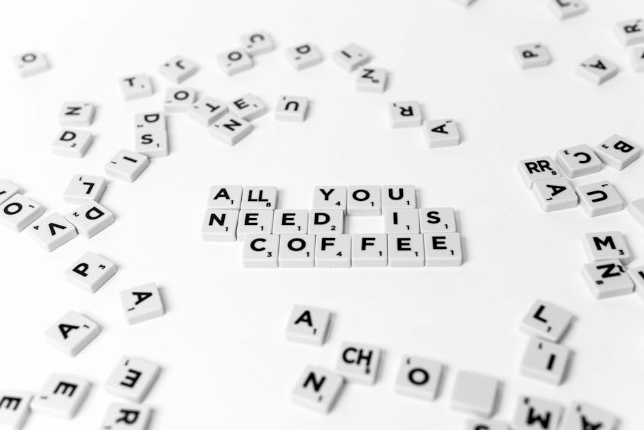 Tessere Scrabble che compongono la frase 'All you need is coffee' su sfondo bianco. Concetto di peso e misura del caffè.