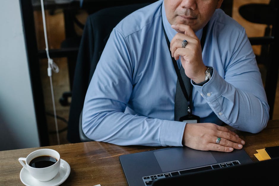 Uomo pensieroso davanti al laptop con caffè, simbolo di concentrazione per ripetizioni online e successo scolastico.